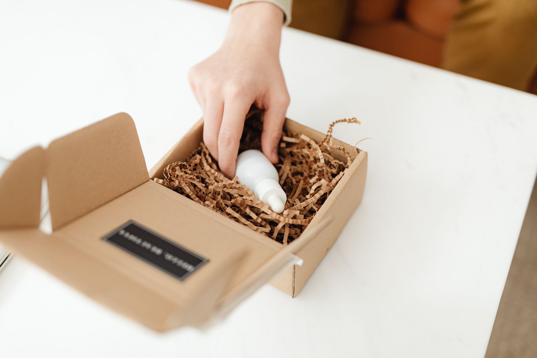 Close-up of a hand unpacking a cardboard box with a product
