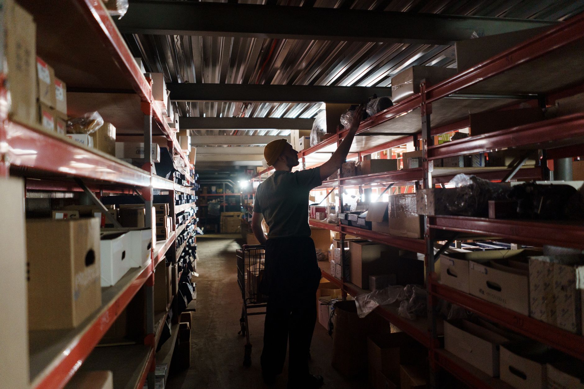 A worker arranging inventory on shelves in a dimly lit wareh
