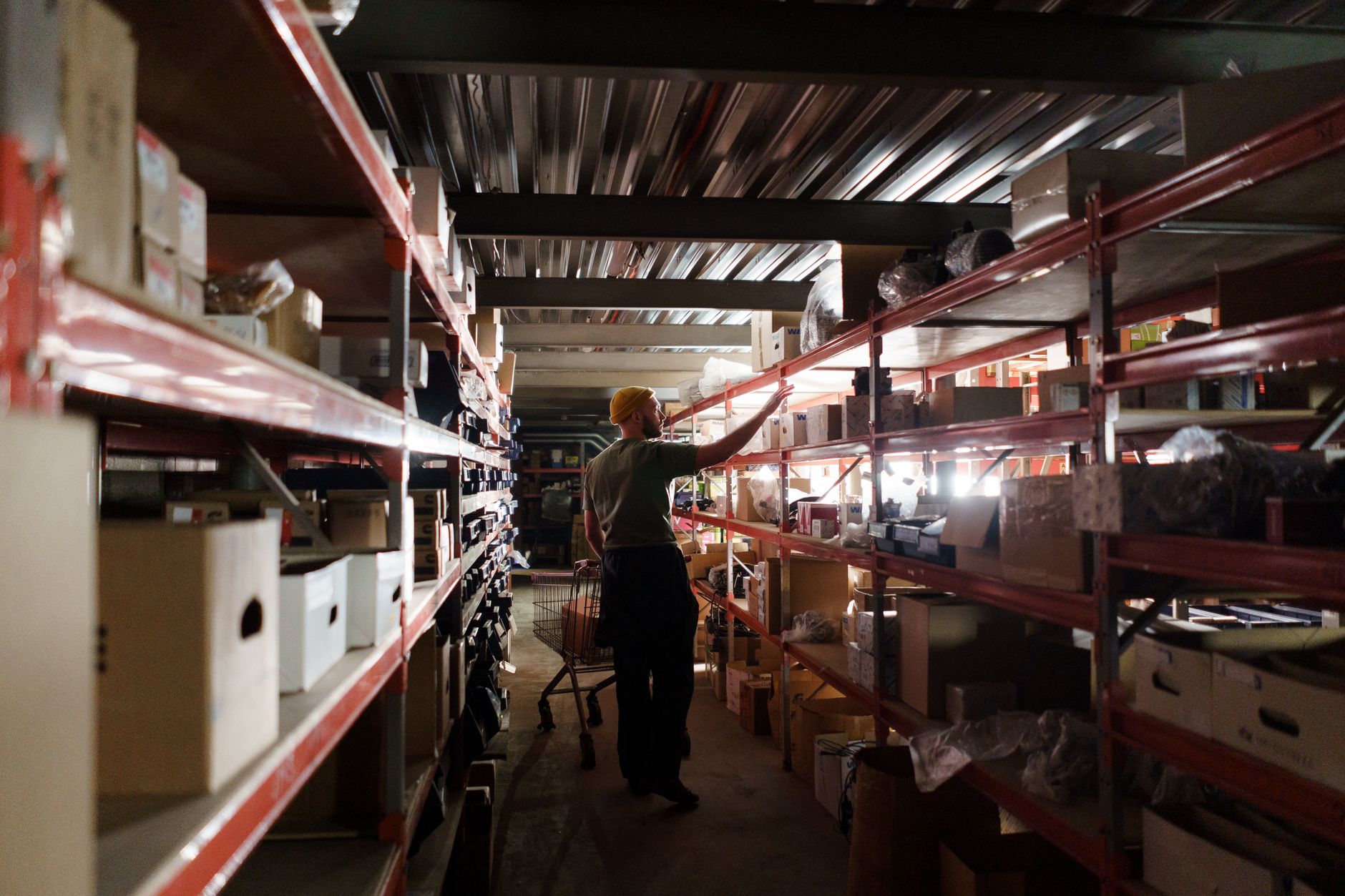 A warehouse worker arranging inventory on metal shelves in a