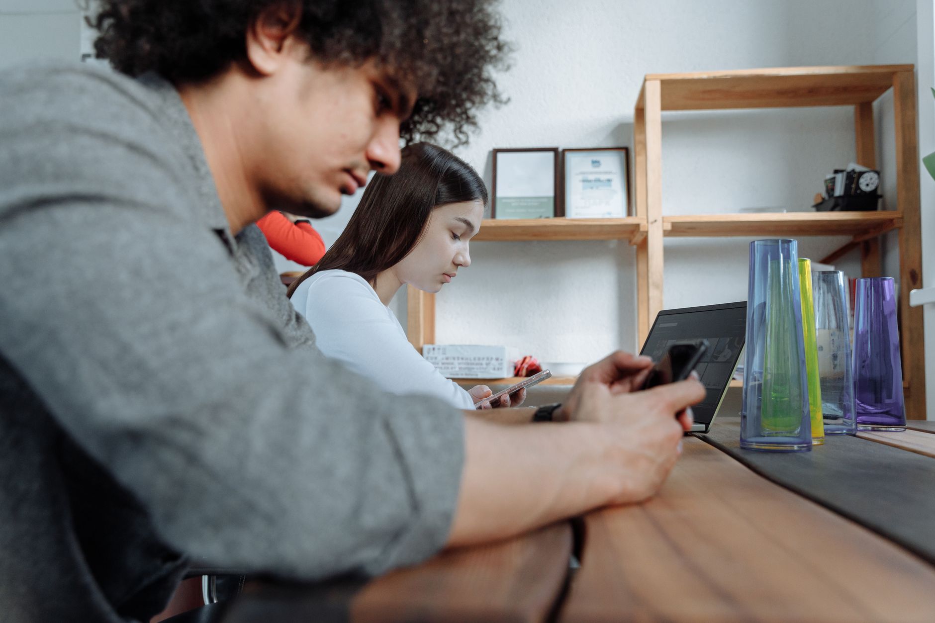 Students focused on smartphones and laptops in a modern clas