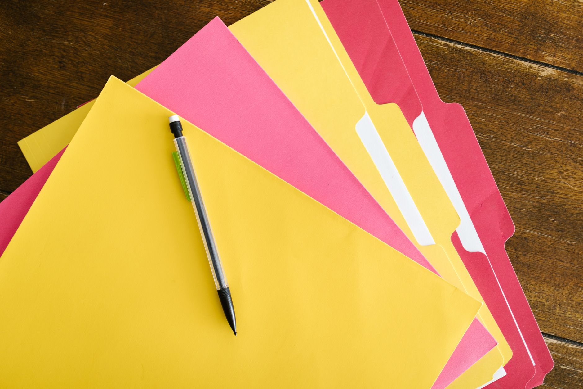Colorful folders and pen arranged on a wooden table for offi