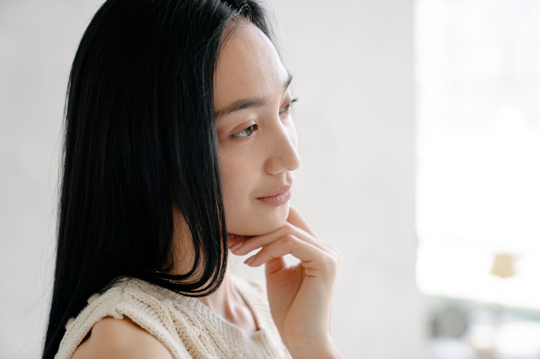 Side view of crop ethnic female with long dark hair touching