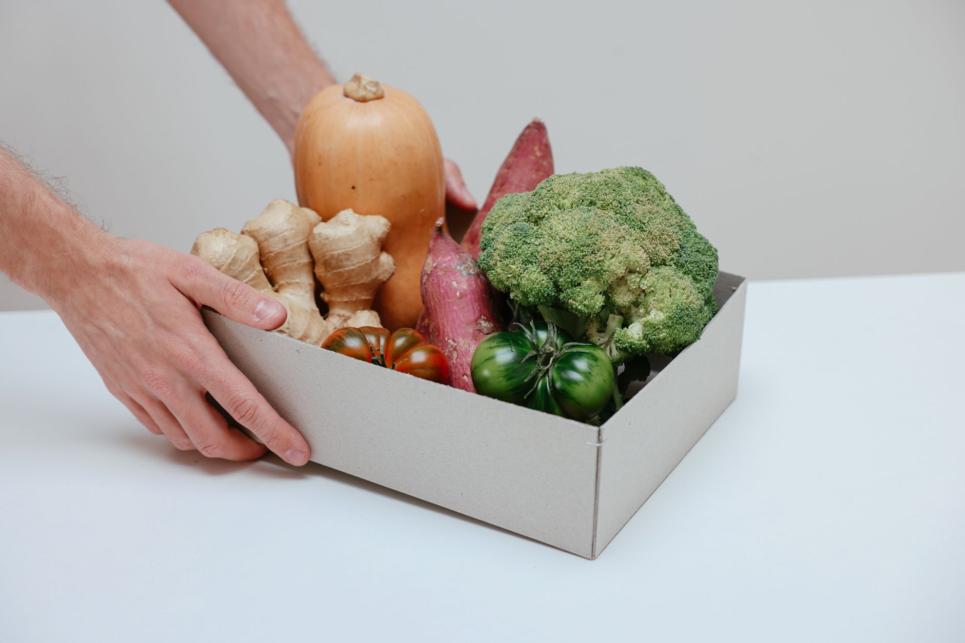 A cardboard box filled with fresh organic vegetables, being