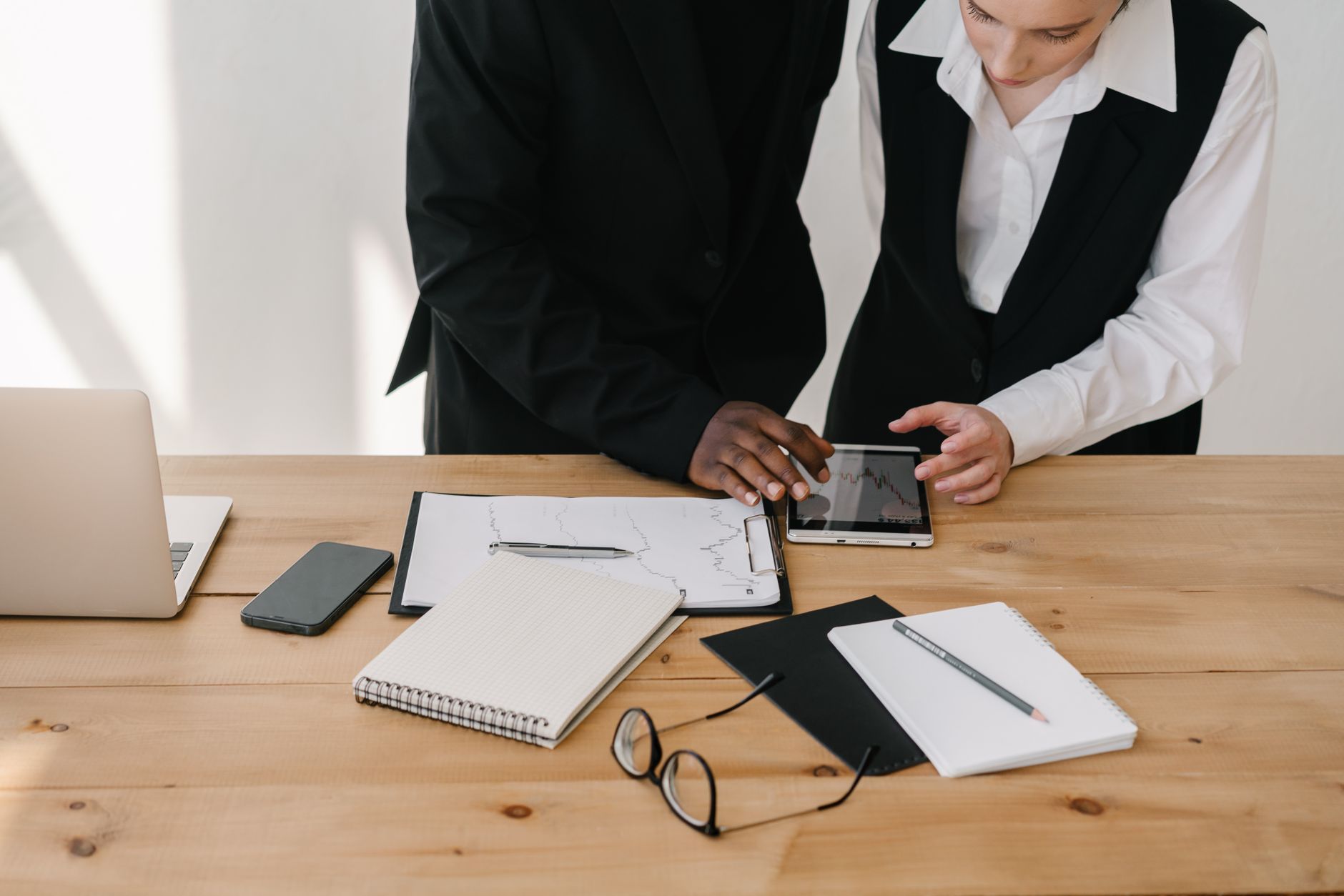 Two professionals collaborating over charts and tablet in a