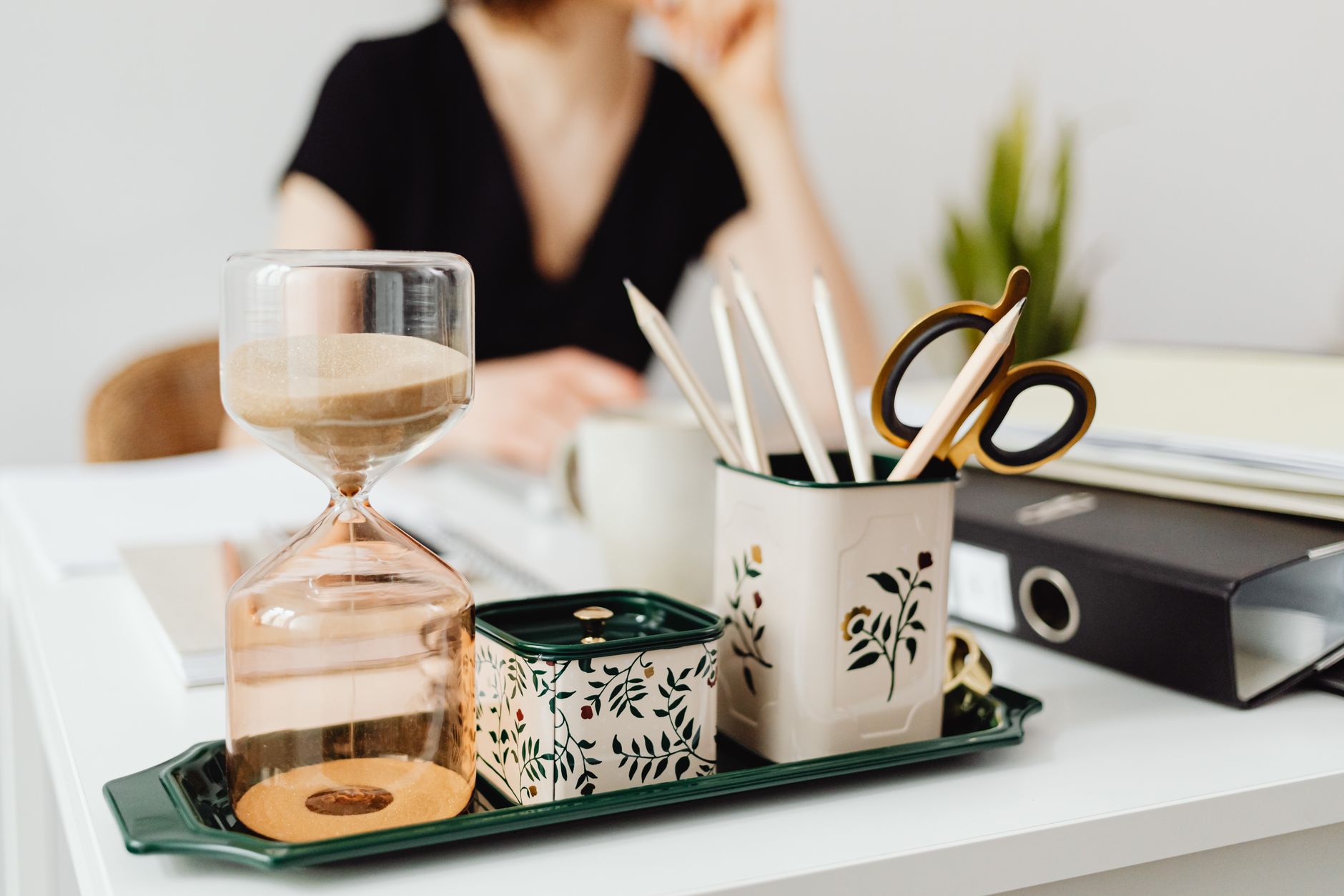 Contemporary office desk setup with hourglass and floral sta