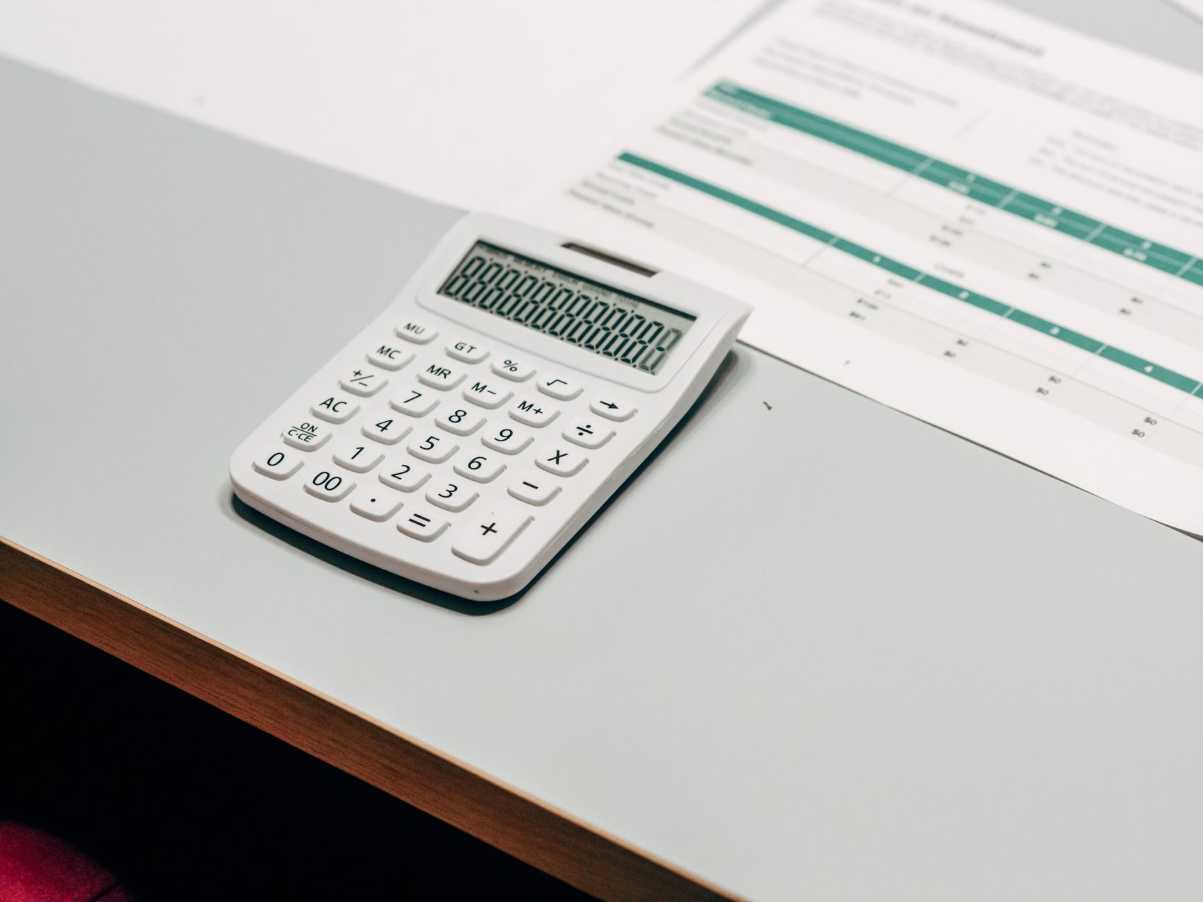 Close-up of a white calculator next to a financial spreadshe