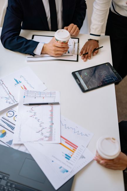 High-angle view of office meeting with charts, coffee, and t