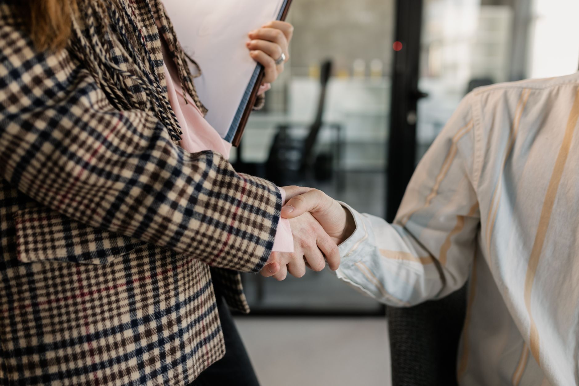 Close-up of a handshake between two professionals in a business environment.