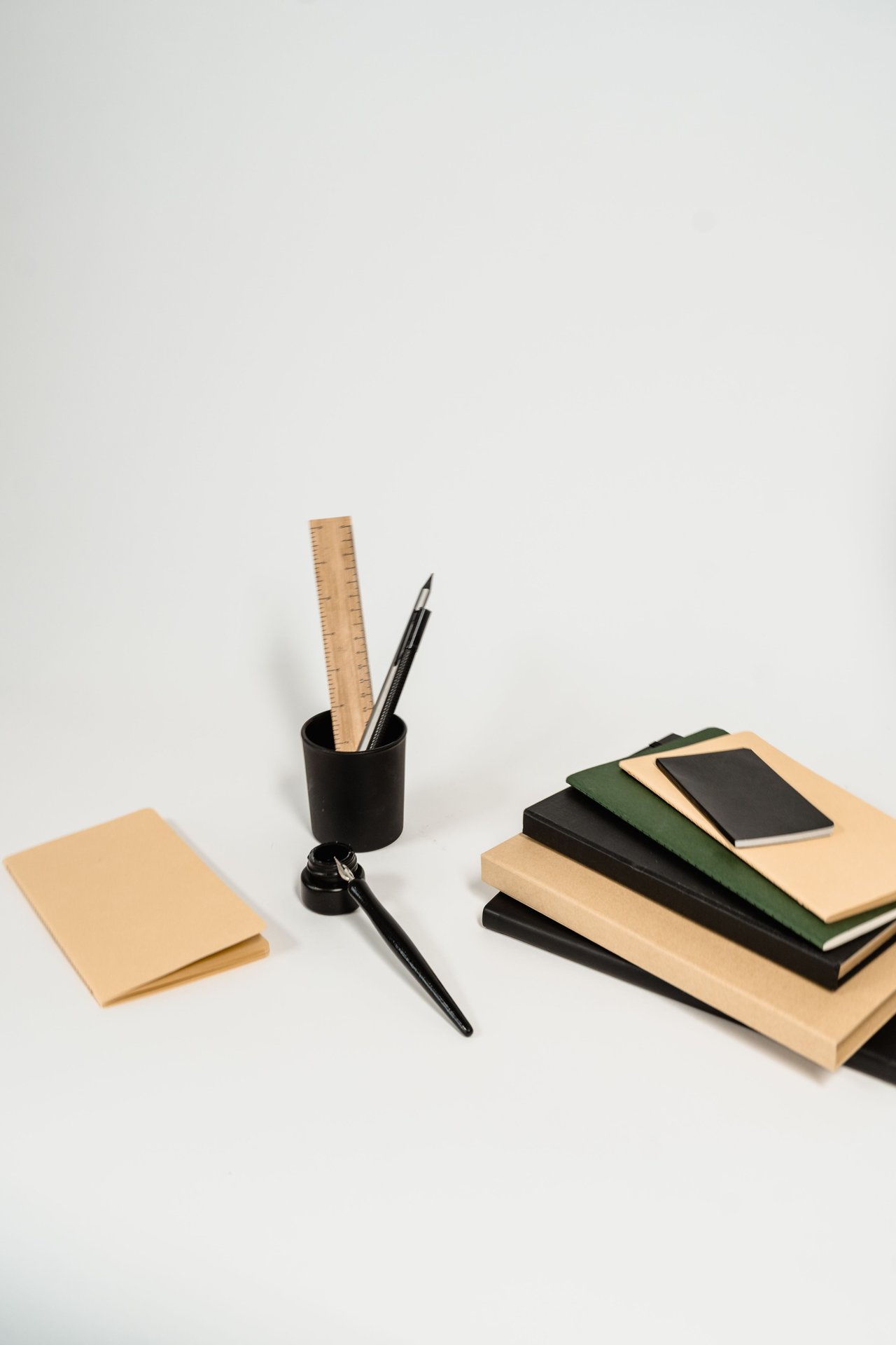 A tidy arrangement of notebooks, pens, and a ruler on a white background, ideal for office themes.