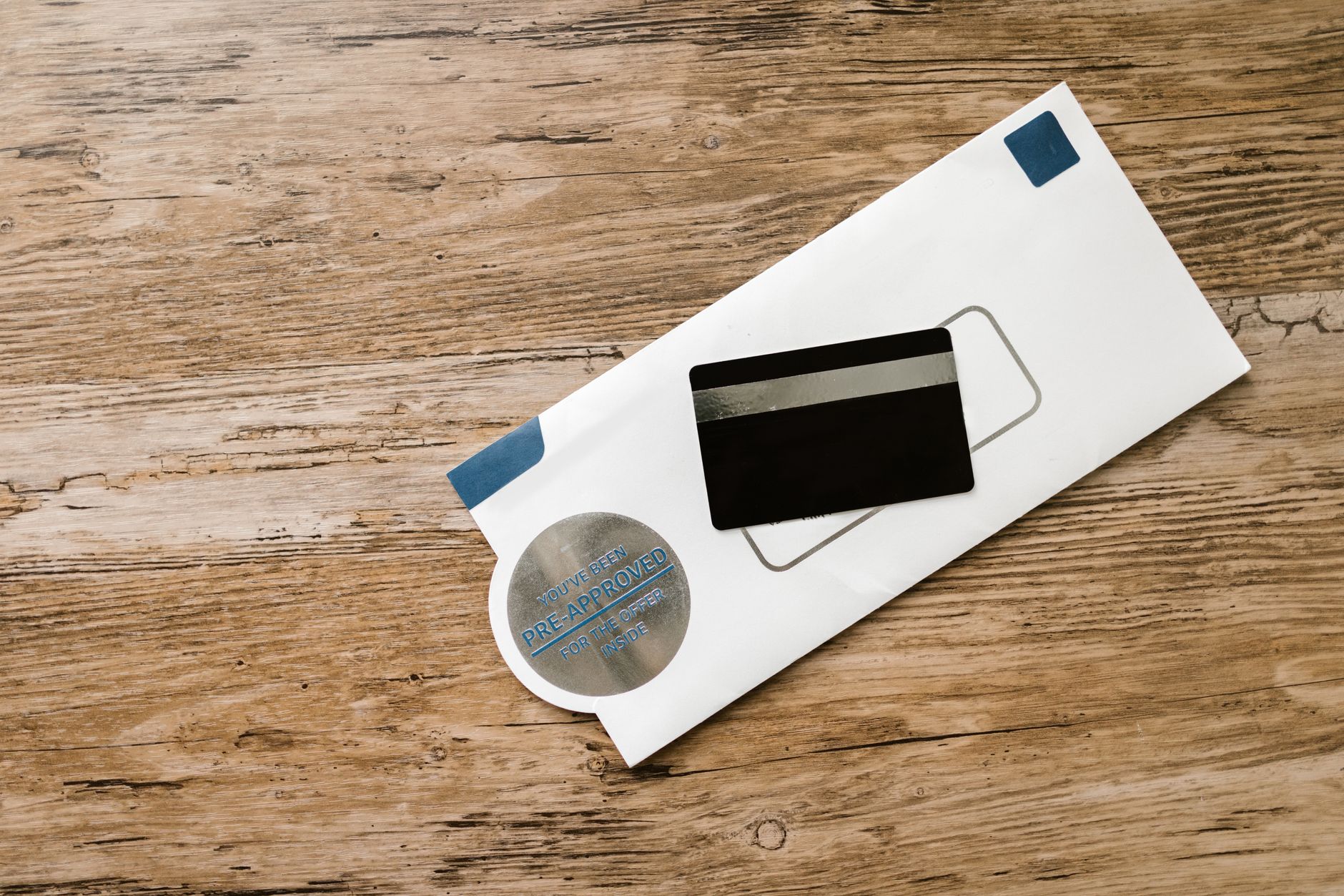 A blank credit card with a pre-approved envelope on a wooden