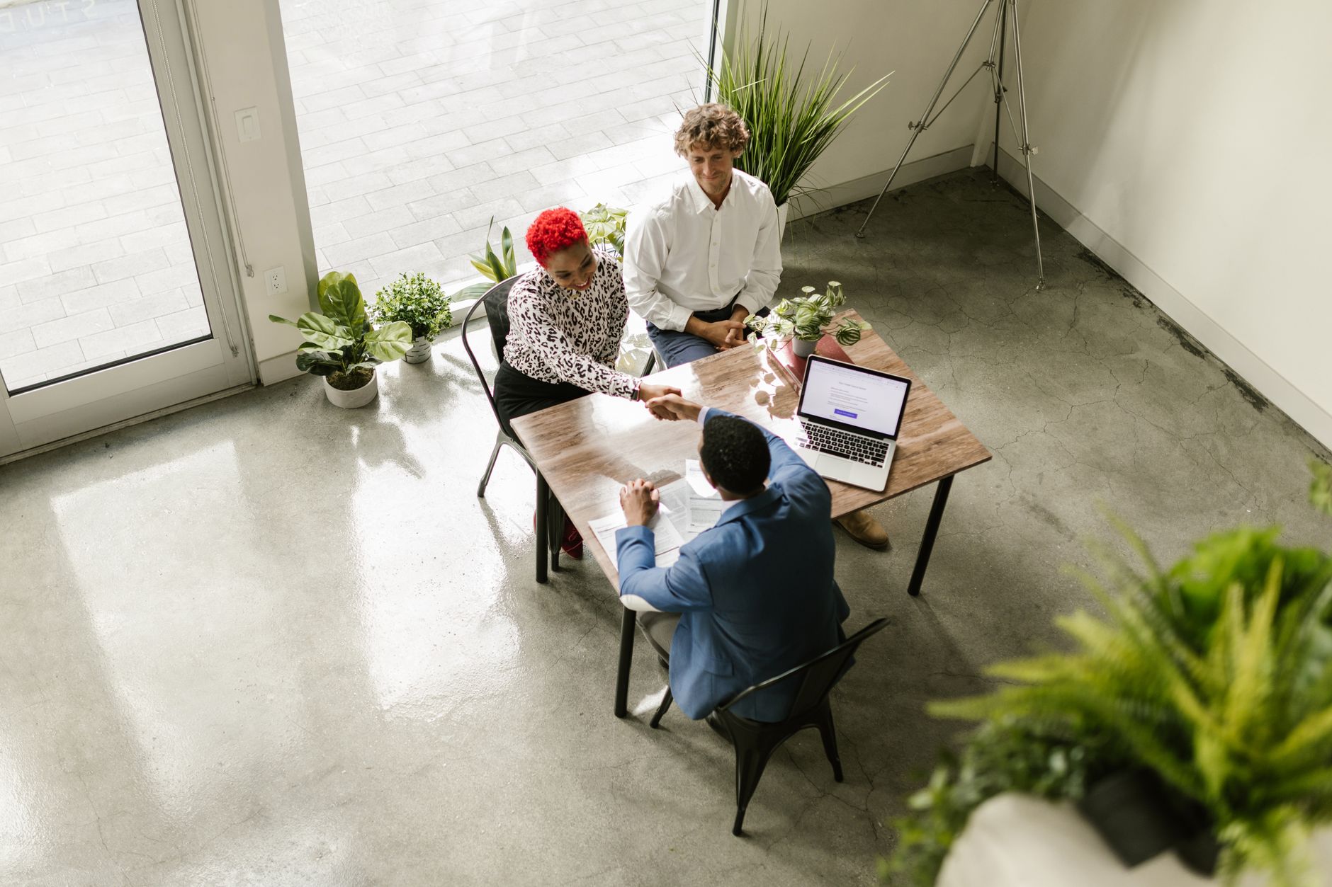 A high-angle view of professionals having a meeting in a modern office setting, shaking hands over a table.