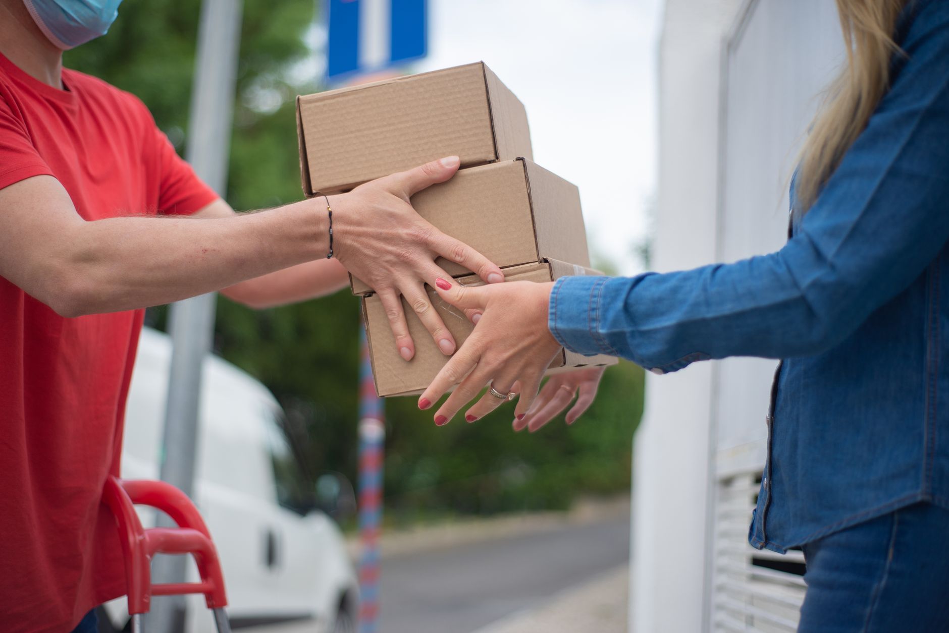 Hands exchanging cardboard boxes during an outdoor delivery