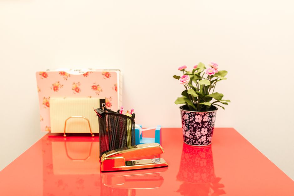 A colorful office desk arrangement featuring a red stapler a