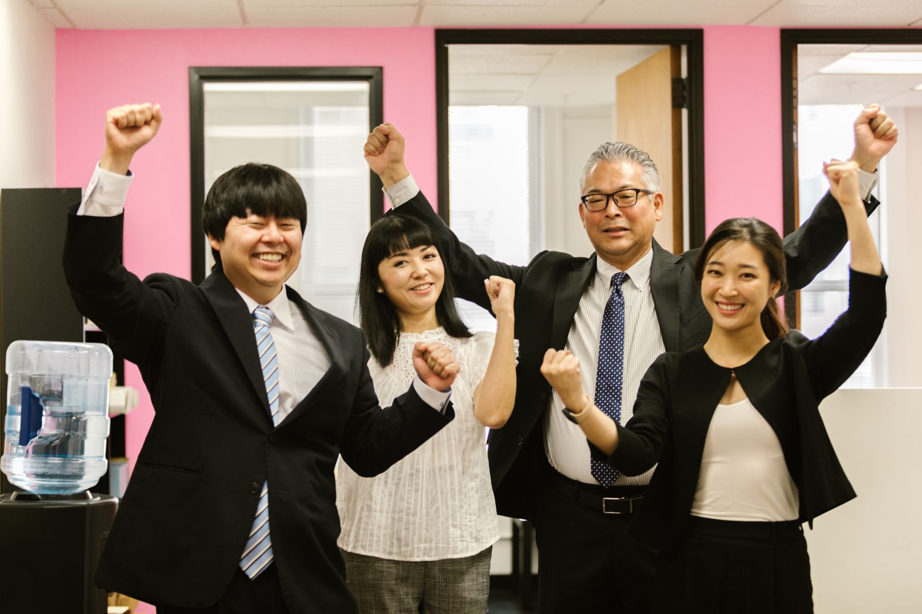 Diverse team of smiling coworkers celebrating success together in an office setting.