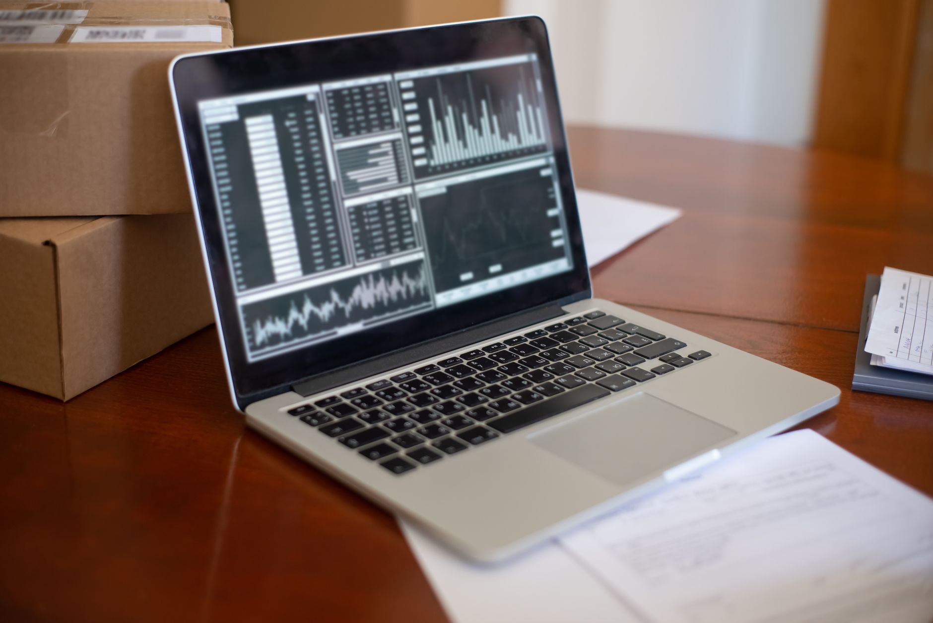 Laptop showing data graphs on wooden table with cardboard bo