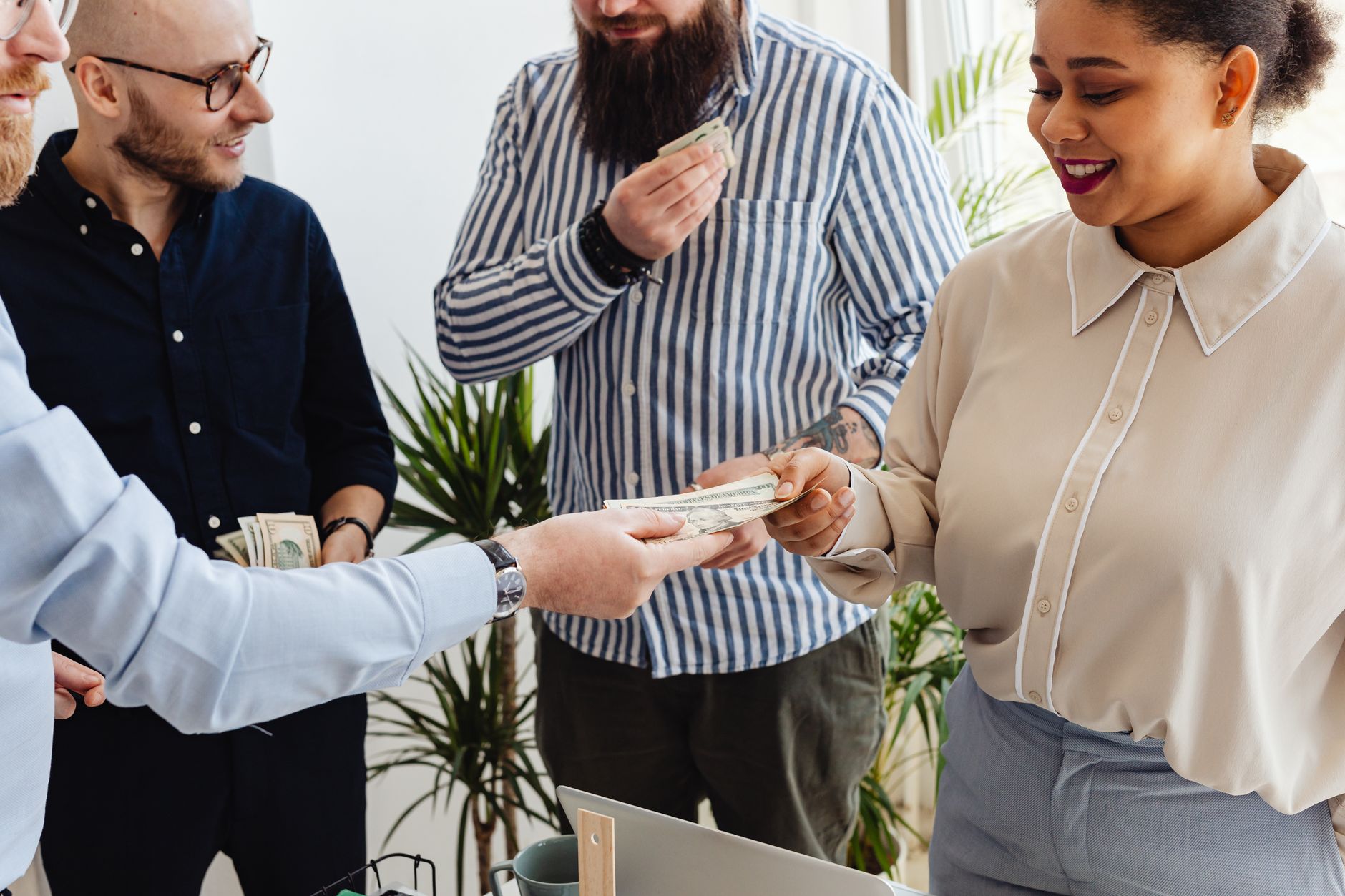 Business professionals exchanging money in a casual office s