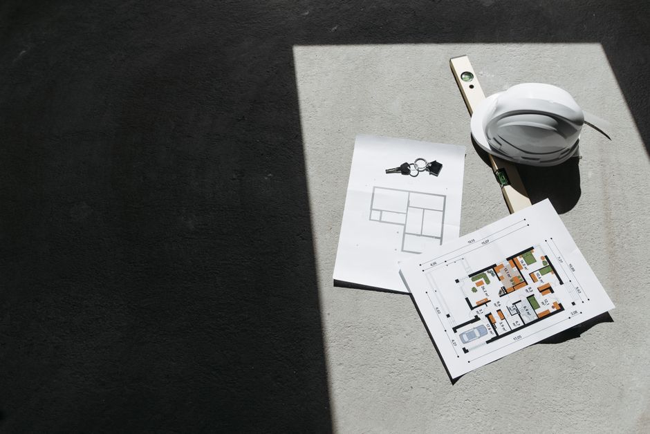 Sunlit construction plans and hard hat on site. Perfect for