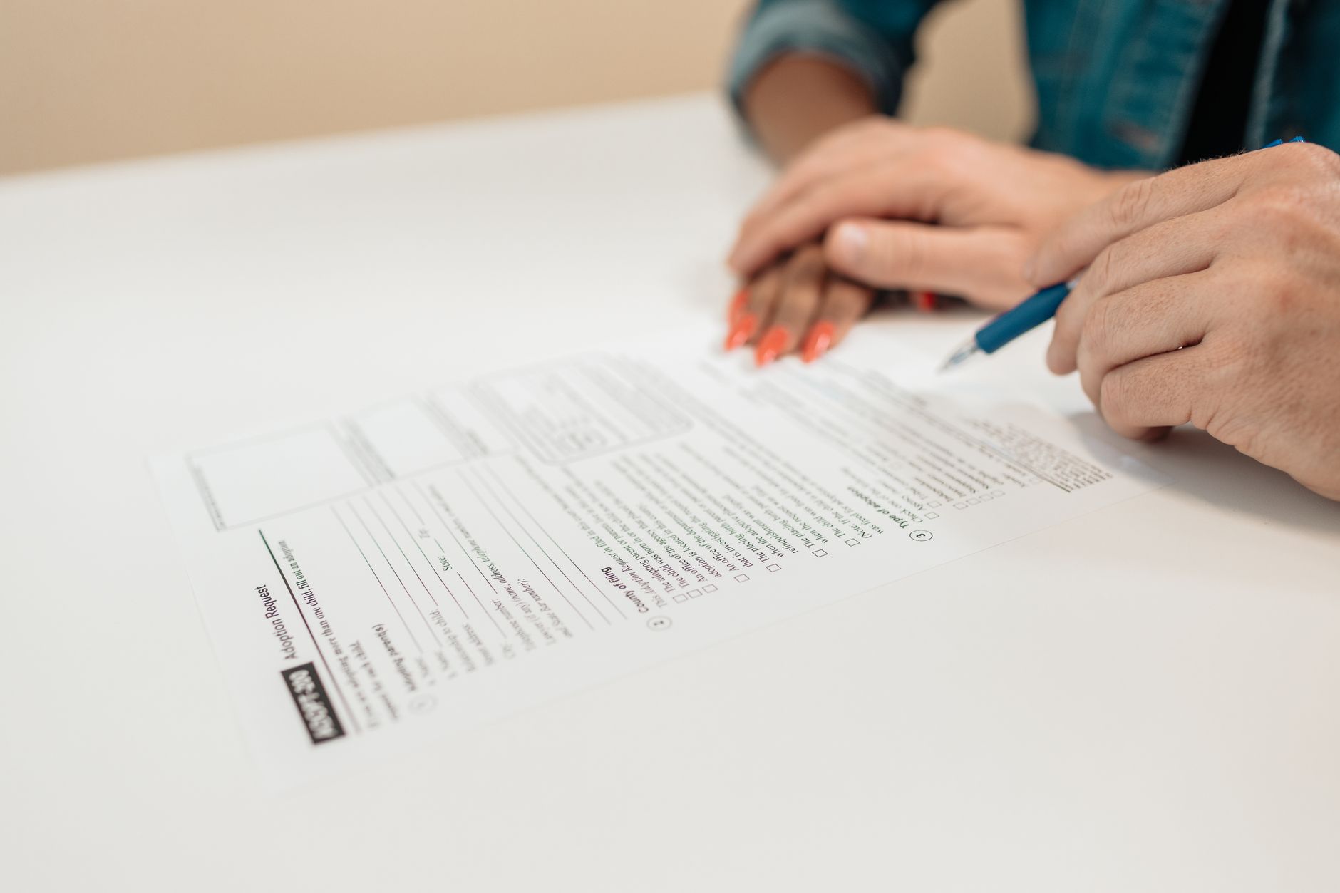 Close-up of hands signing adoption papers in an office envir