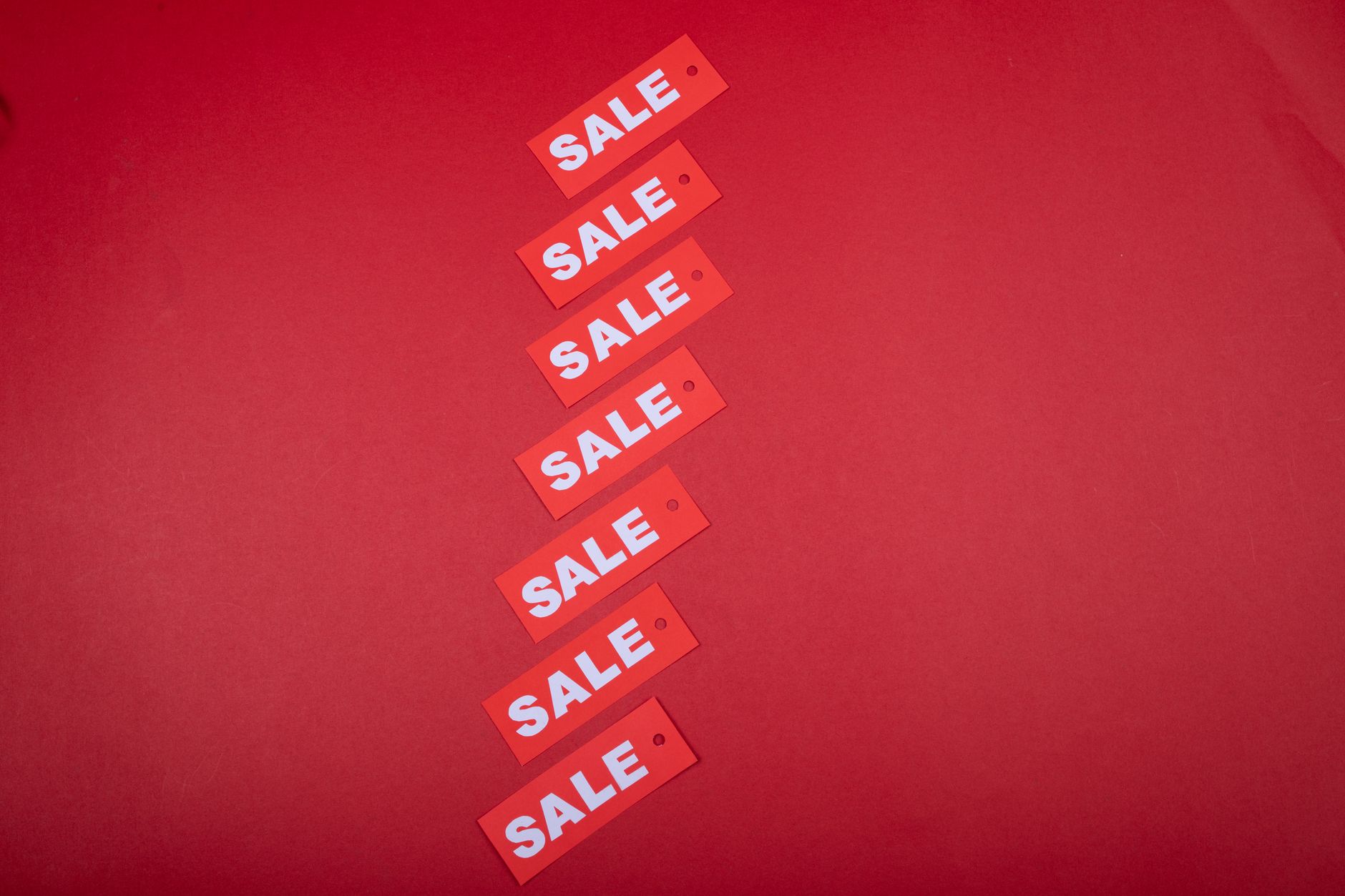 Top view of red sale tags arranged on a vibrant red backgrou