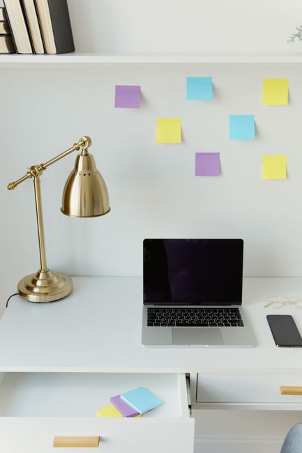 Organized desk space featuring a laptop, brass lamp, and col