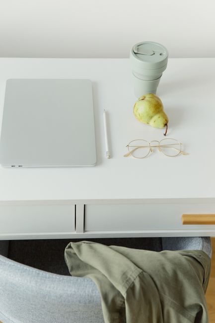 A clean and organized workspace featuring a laptop, eyeglass