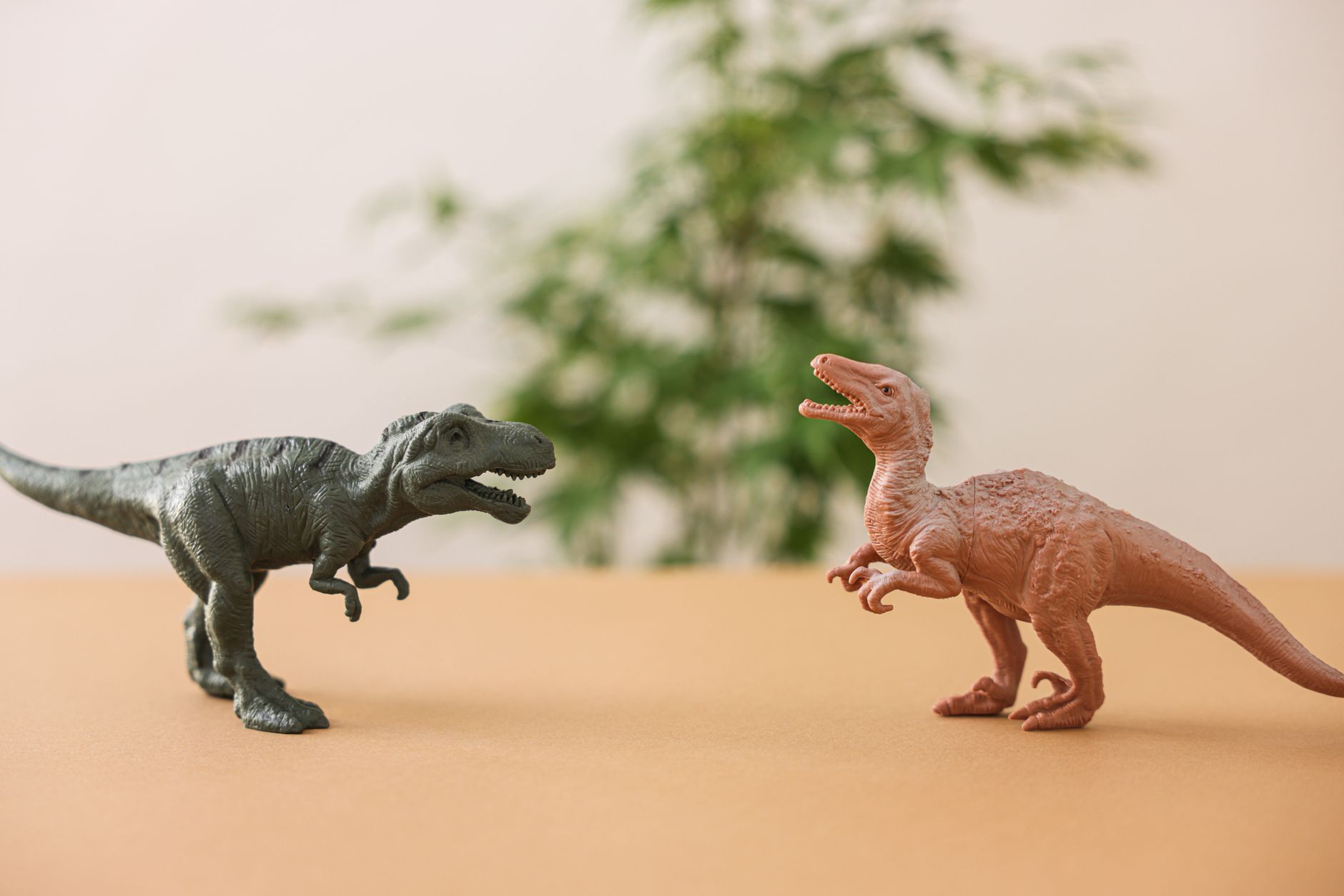 Two toy dinosaur figures set against a natural background on