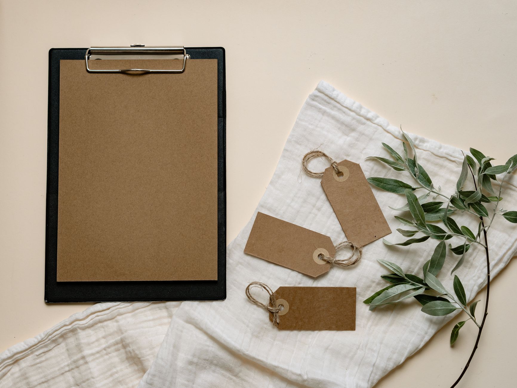 A minimalist flat lay of brown clipboard and tags with green