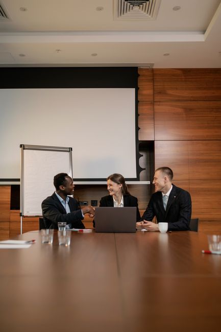 Three professionals engaging in a handshake during a busines