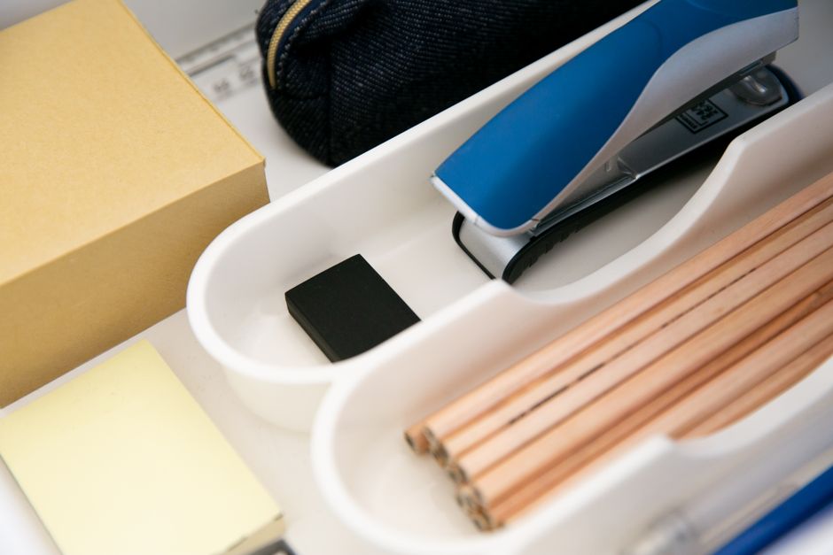 Close-up of an office drawer organized with pencils, stapler