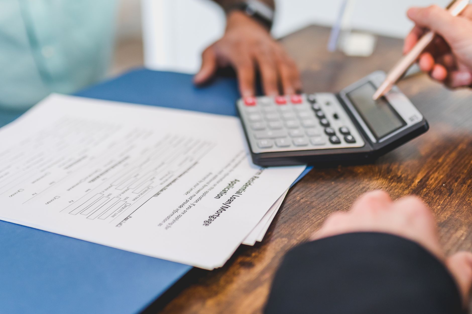 Hands using a calculator with real estate documents on a des