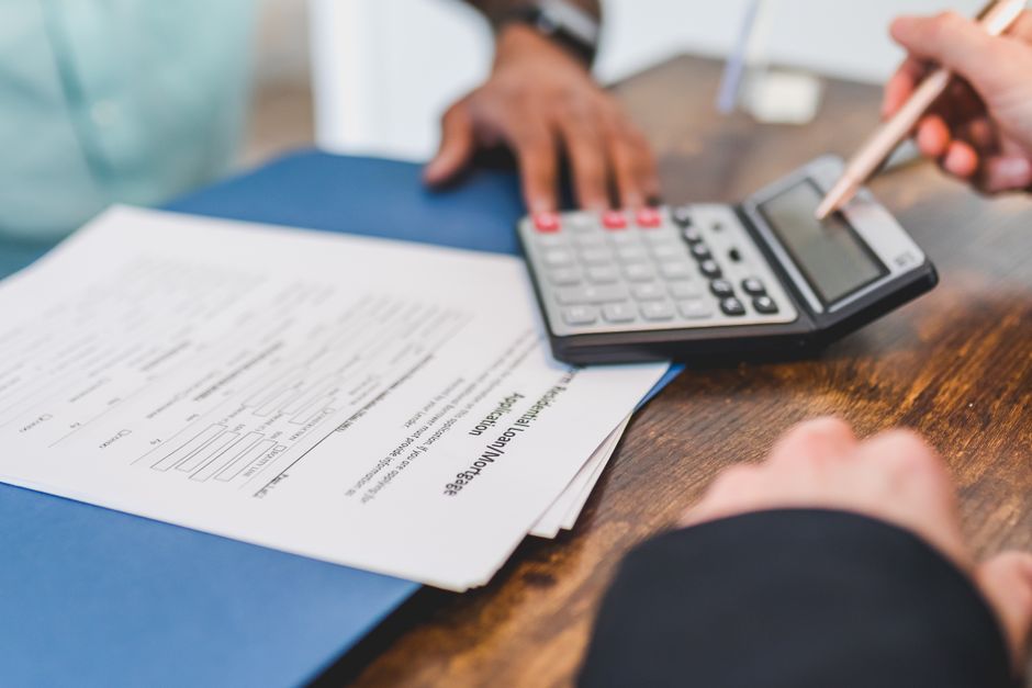 Hands using a calculator with real estate documents on a des