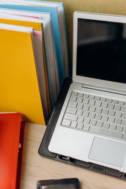 A neat office setup featuring a laptop, colorful files, and