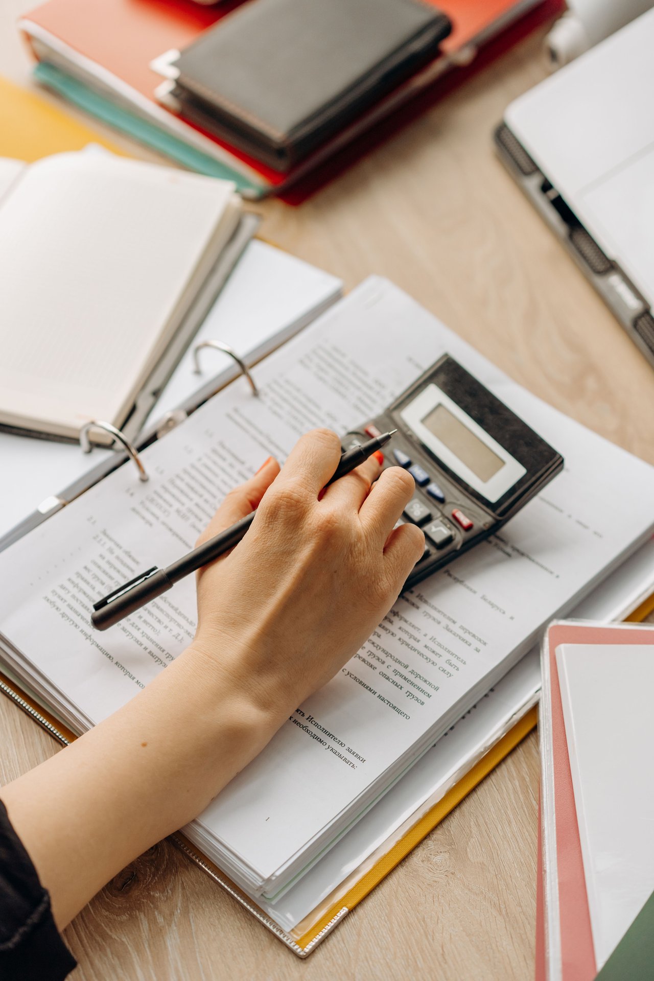 Close-up of a hand using a calculator on documents in an off