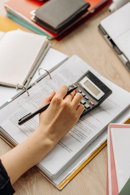 Close-up of a hand using a calculator on documents in an off