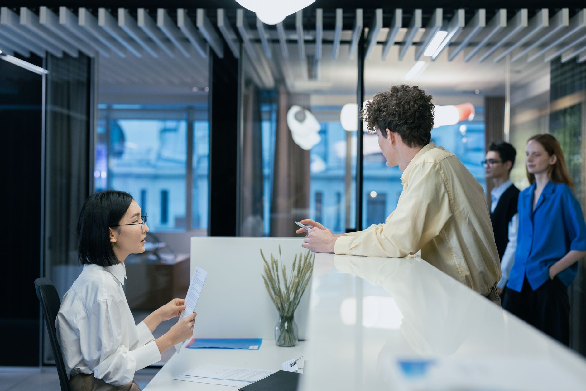 Employees interacting at a sleek office reception desk, fost
