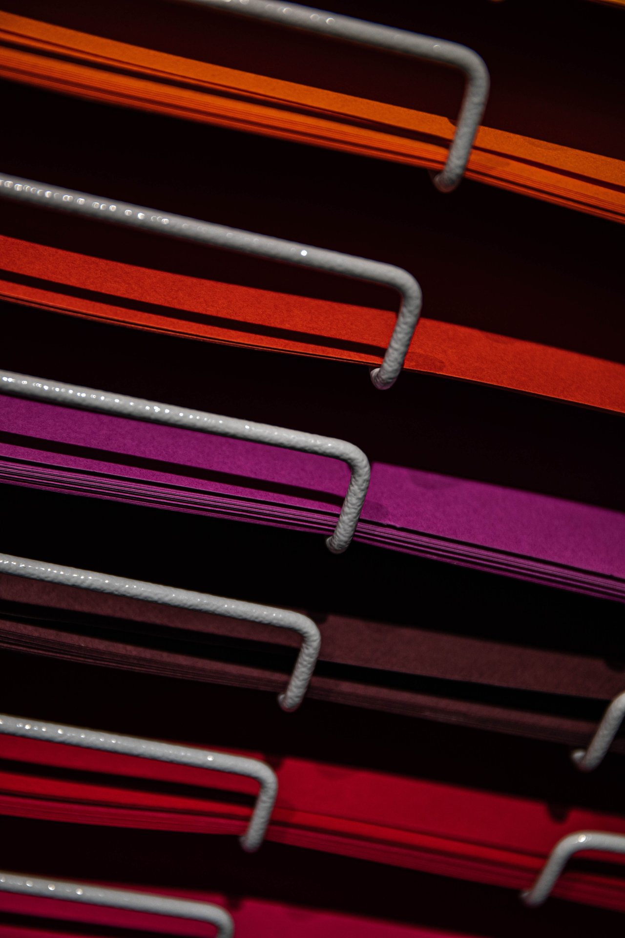 Stack of vibrant colored papers arranged neatly on a metal r