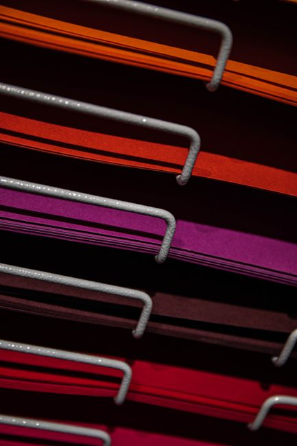 Stack of vibrant colored papers arranged neatly on a metal r