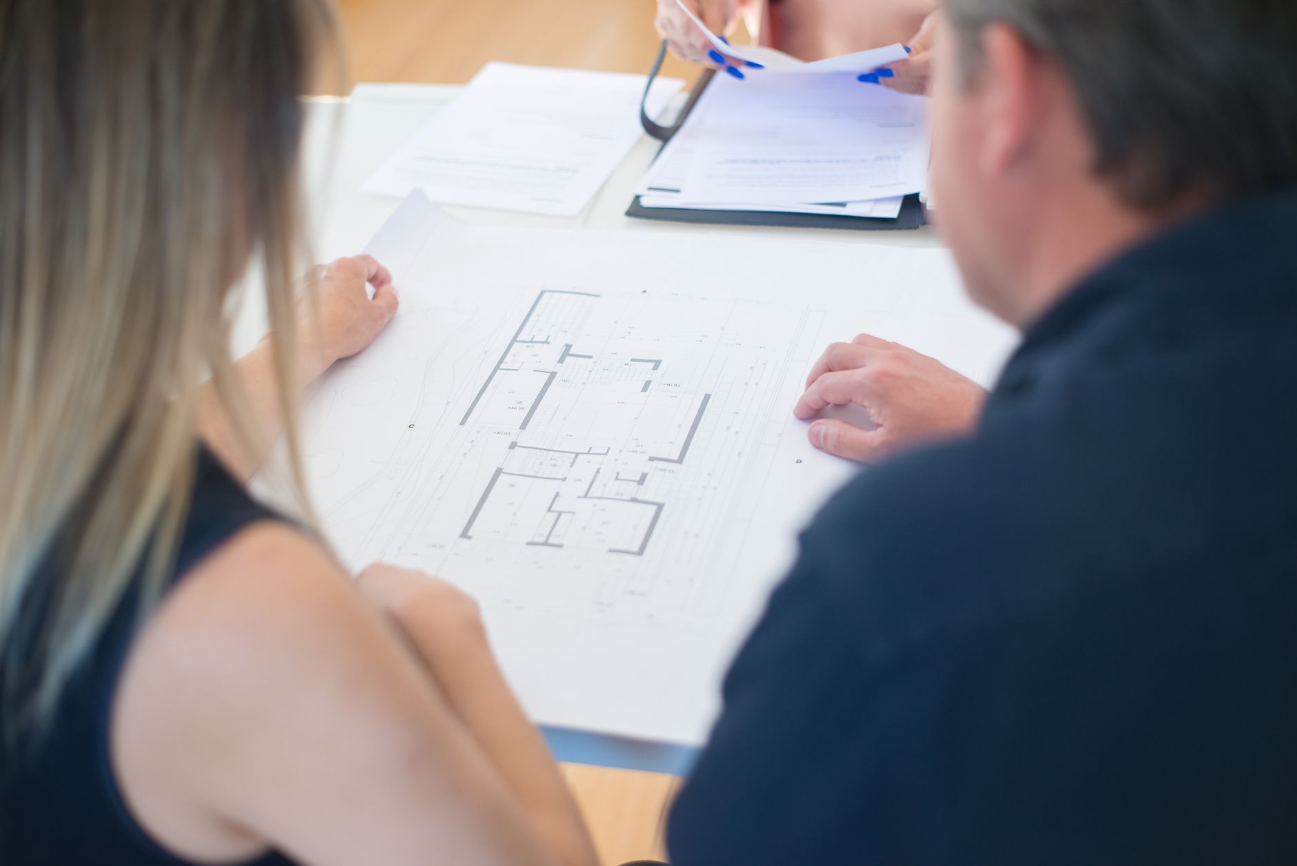 Architects discussing a detailed floor plan in an office set