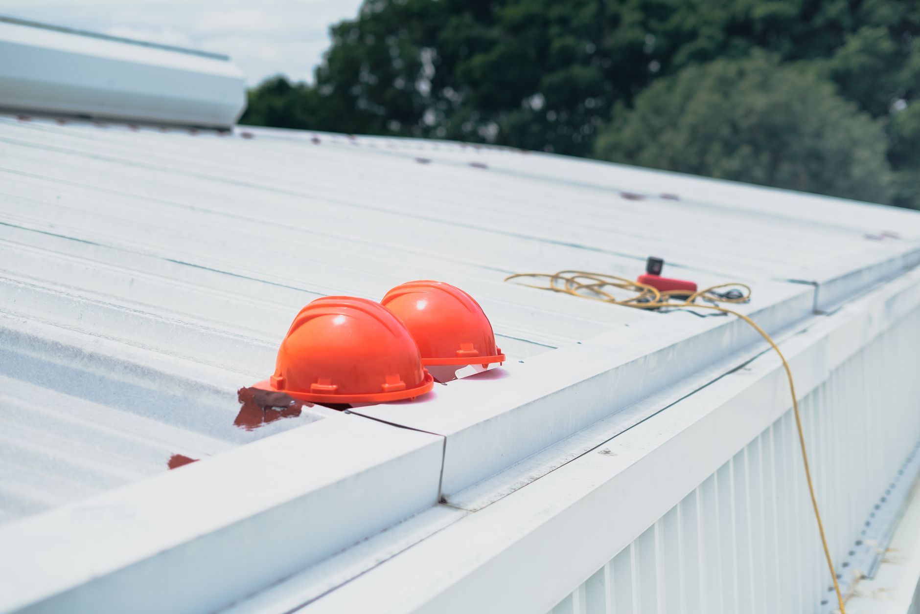 Red hard hats and safety equipment on a metal roof, emphasiz