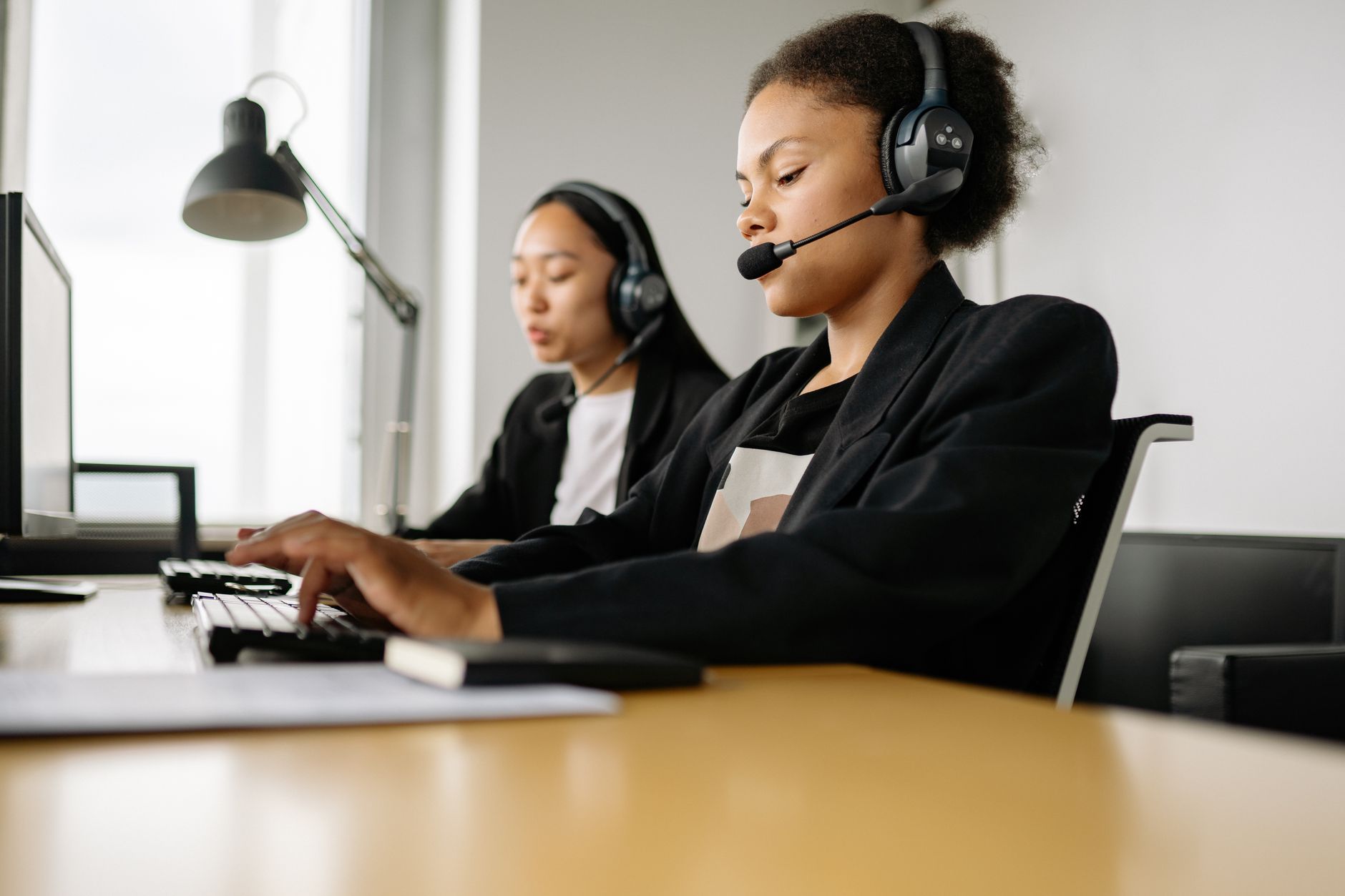 Two call center agents working at desks in an office setting