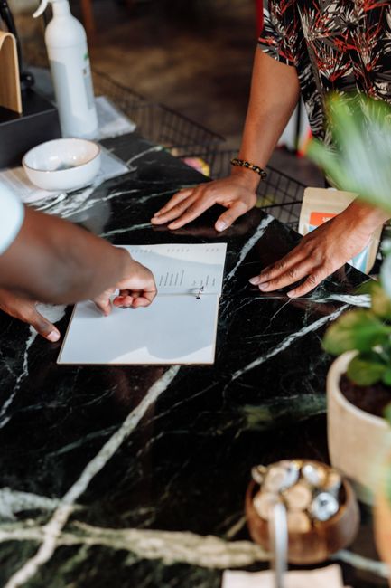Hands pointing to a menu on a polished black countertop in a