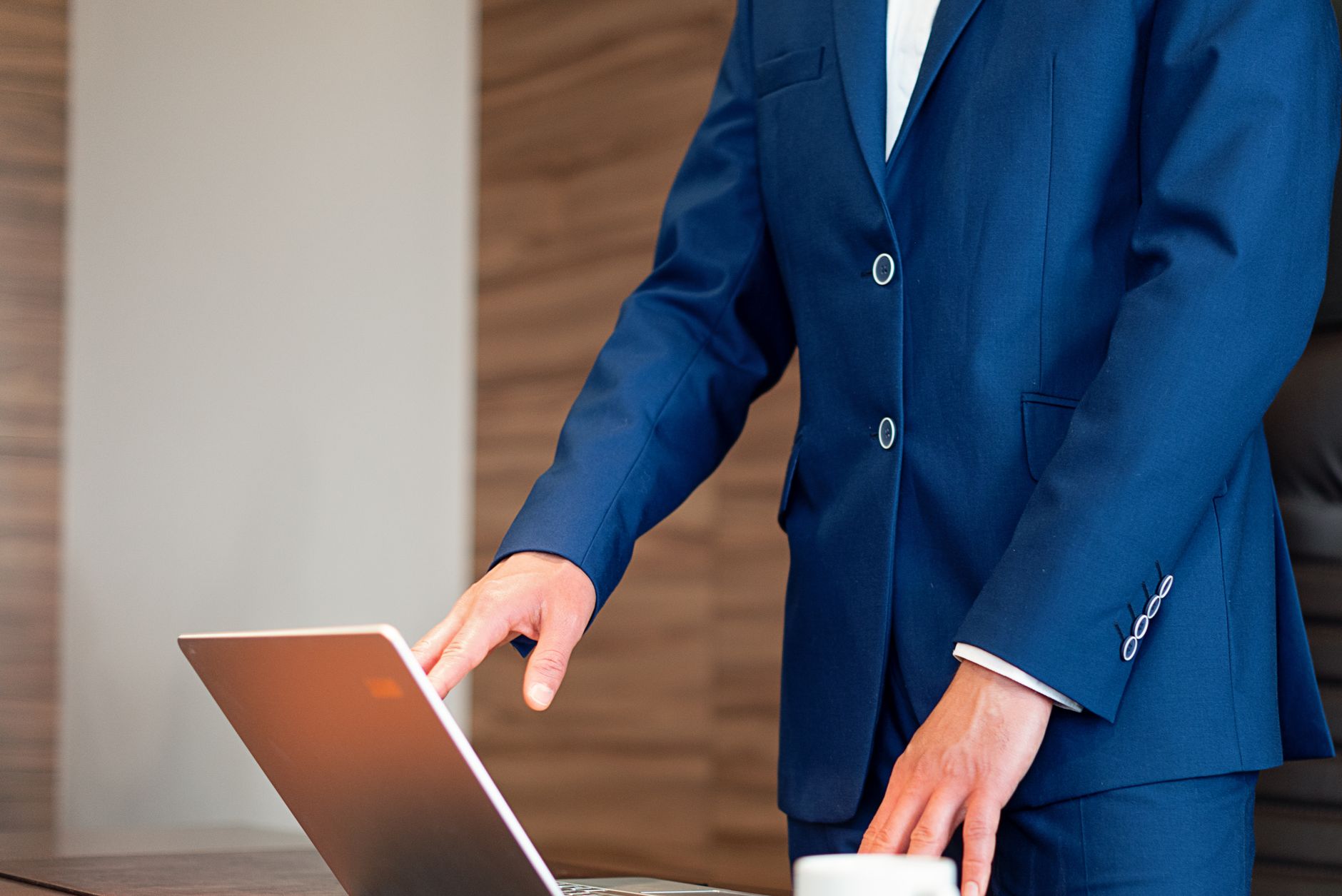 Business professional in a suit using a laptop on a desk in