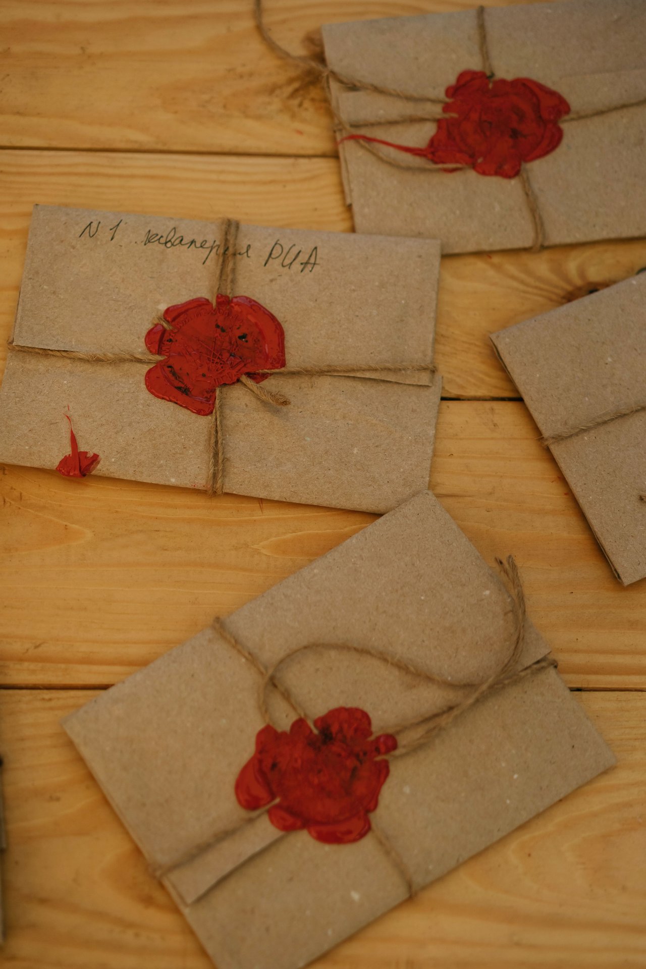 Artistic arrangement of recycled envelopes sealed with red wax on a wooden table.