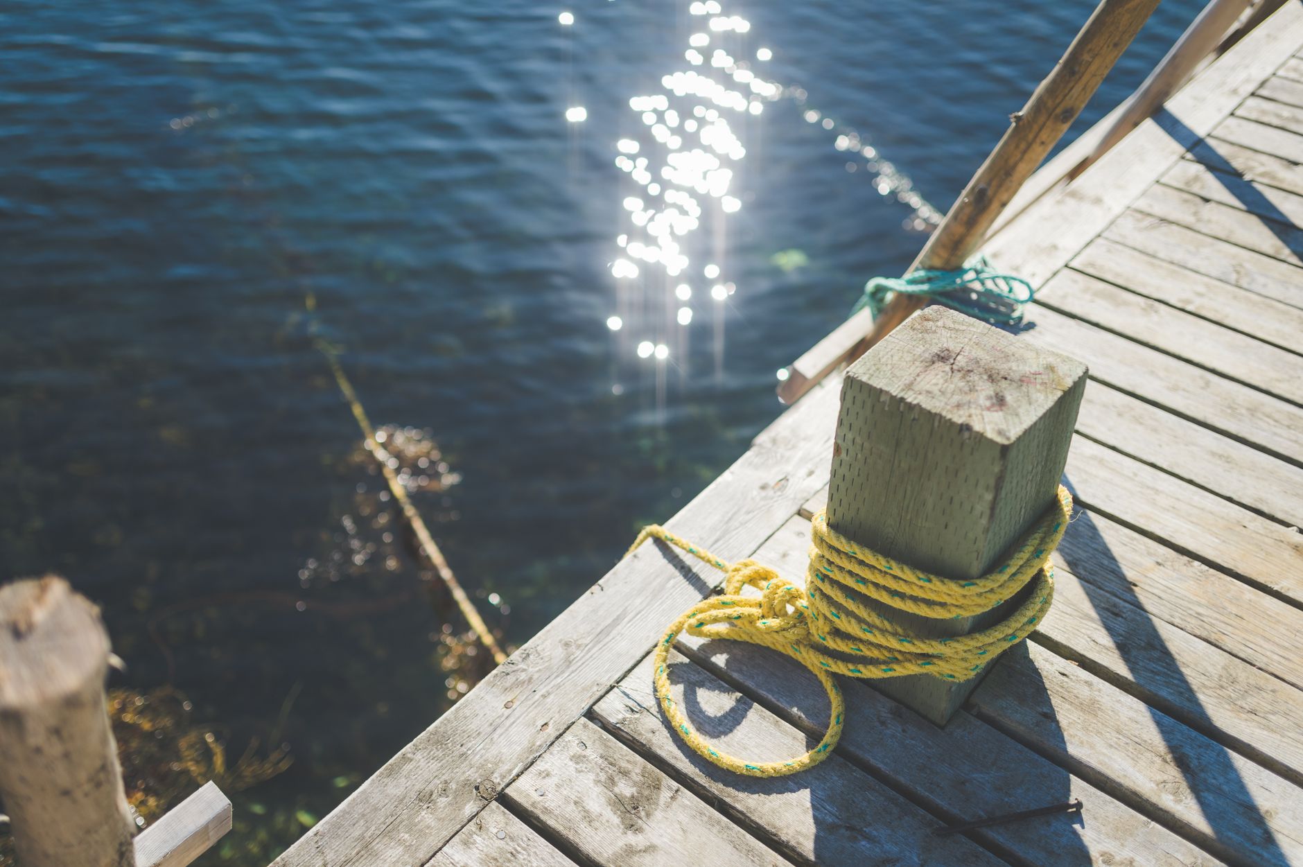 A serene view of a wooden dock with a yellow rope and sparkl