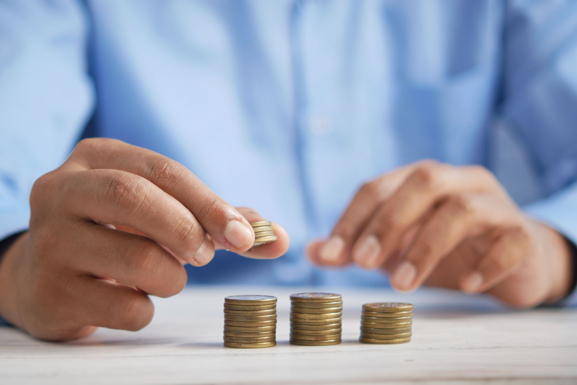 Close-up of hands stacking gold coins, symbolizing financial