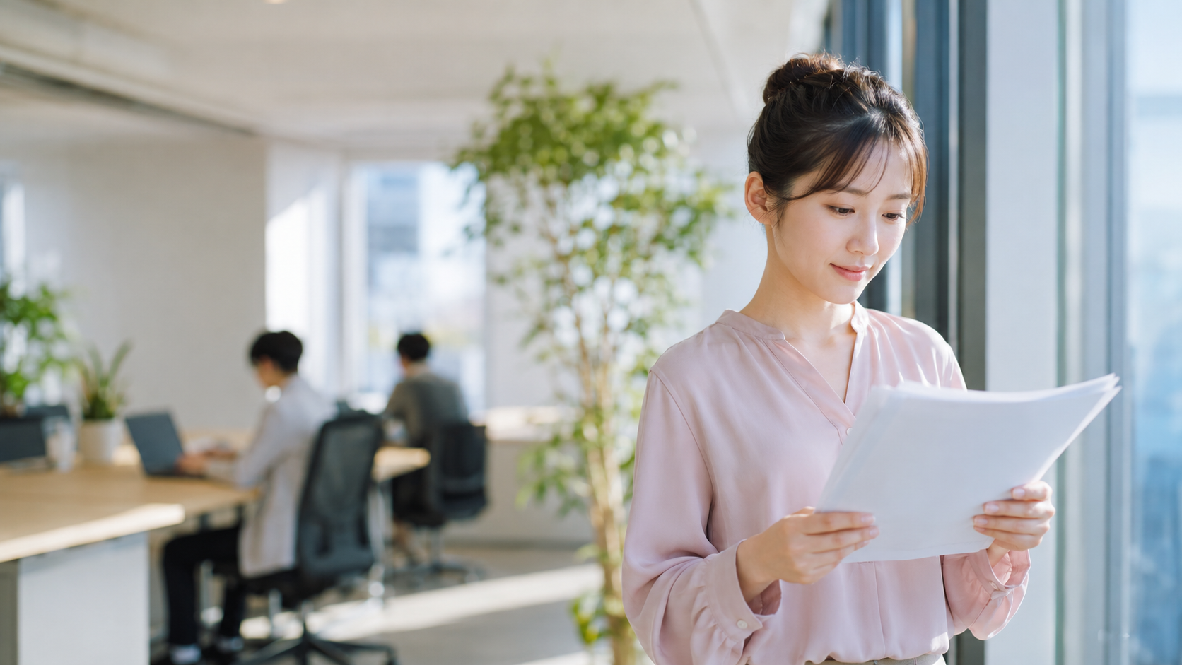 20代後半の日本人女性が窓際での書類確認場面