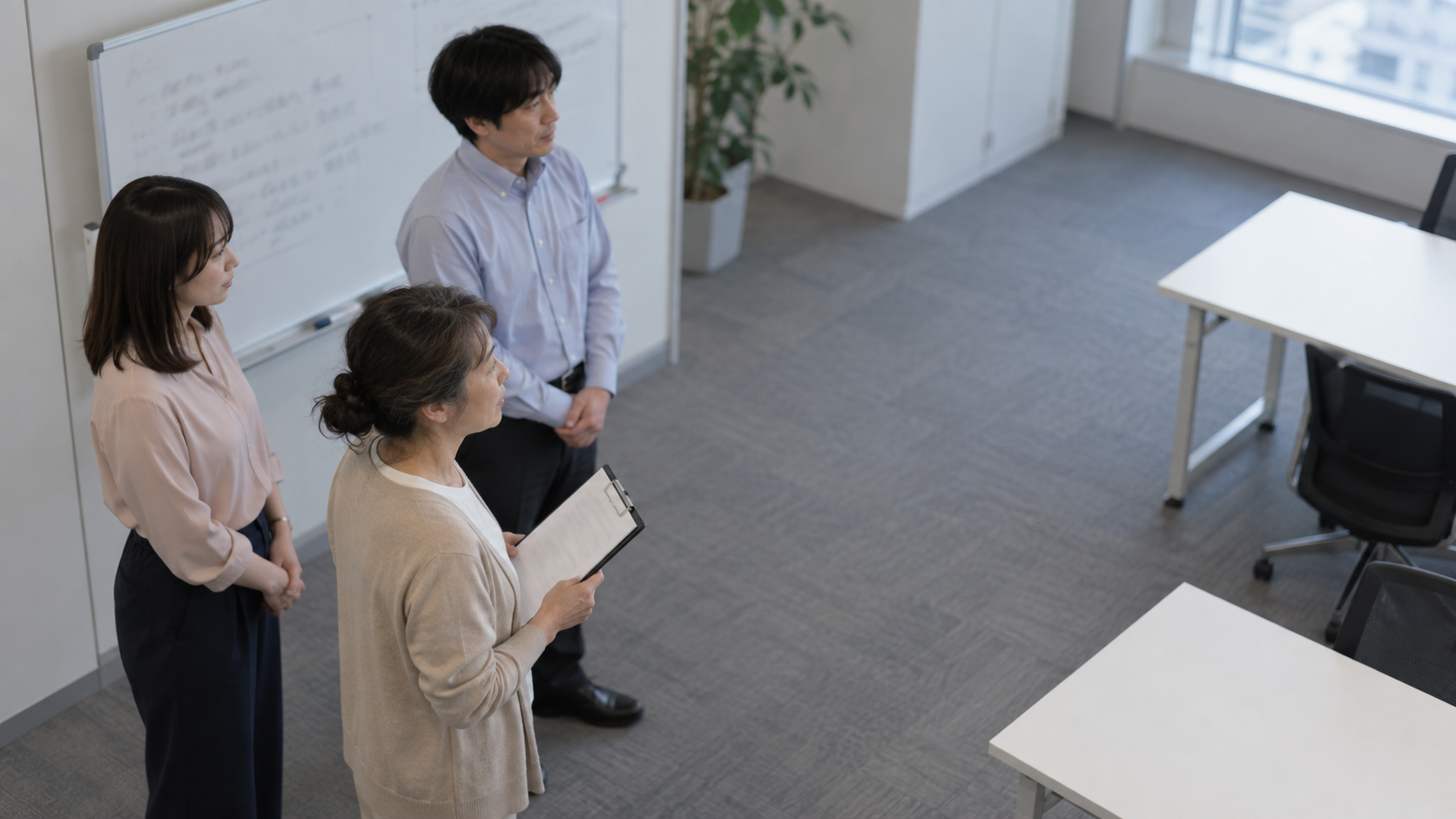 50代前半の日本人女性が朝礼での連絡をしている場面