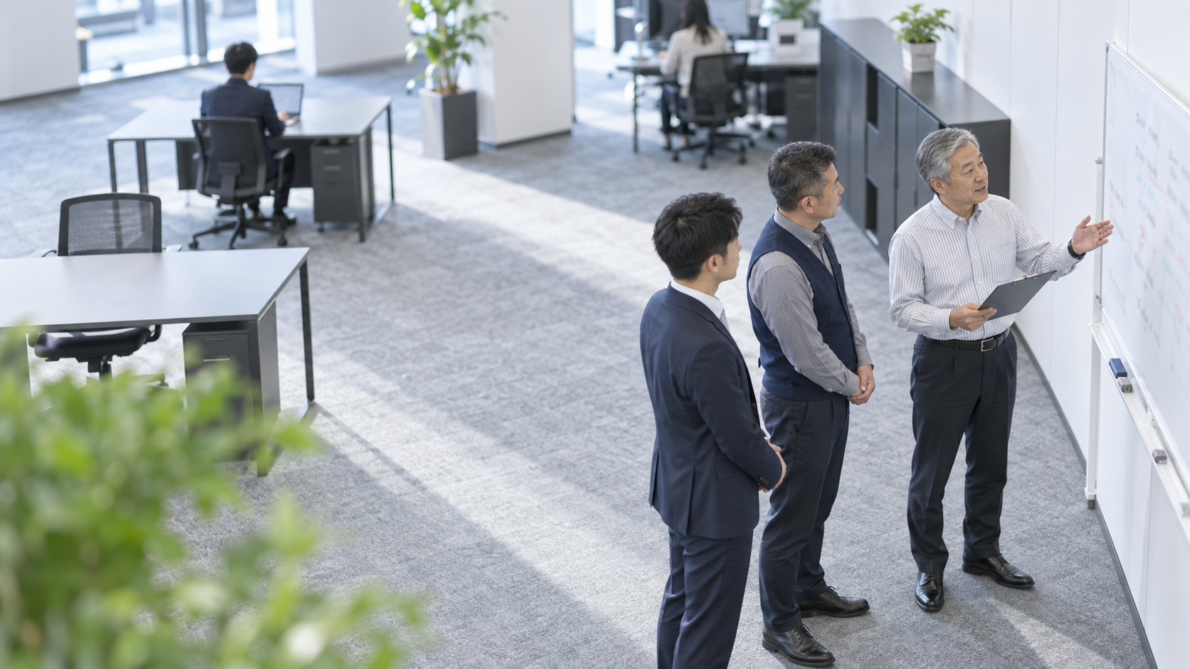 50代前半の日本人男性が朝礼での連絡をしている場面