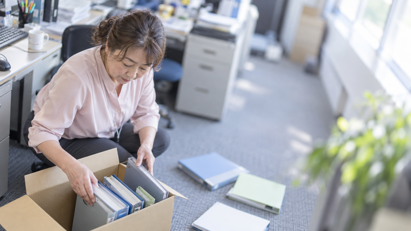 50代後半の日本人女性が年度末の書類整理をしている場面