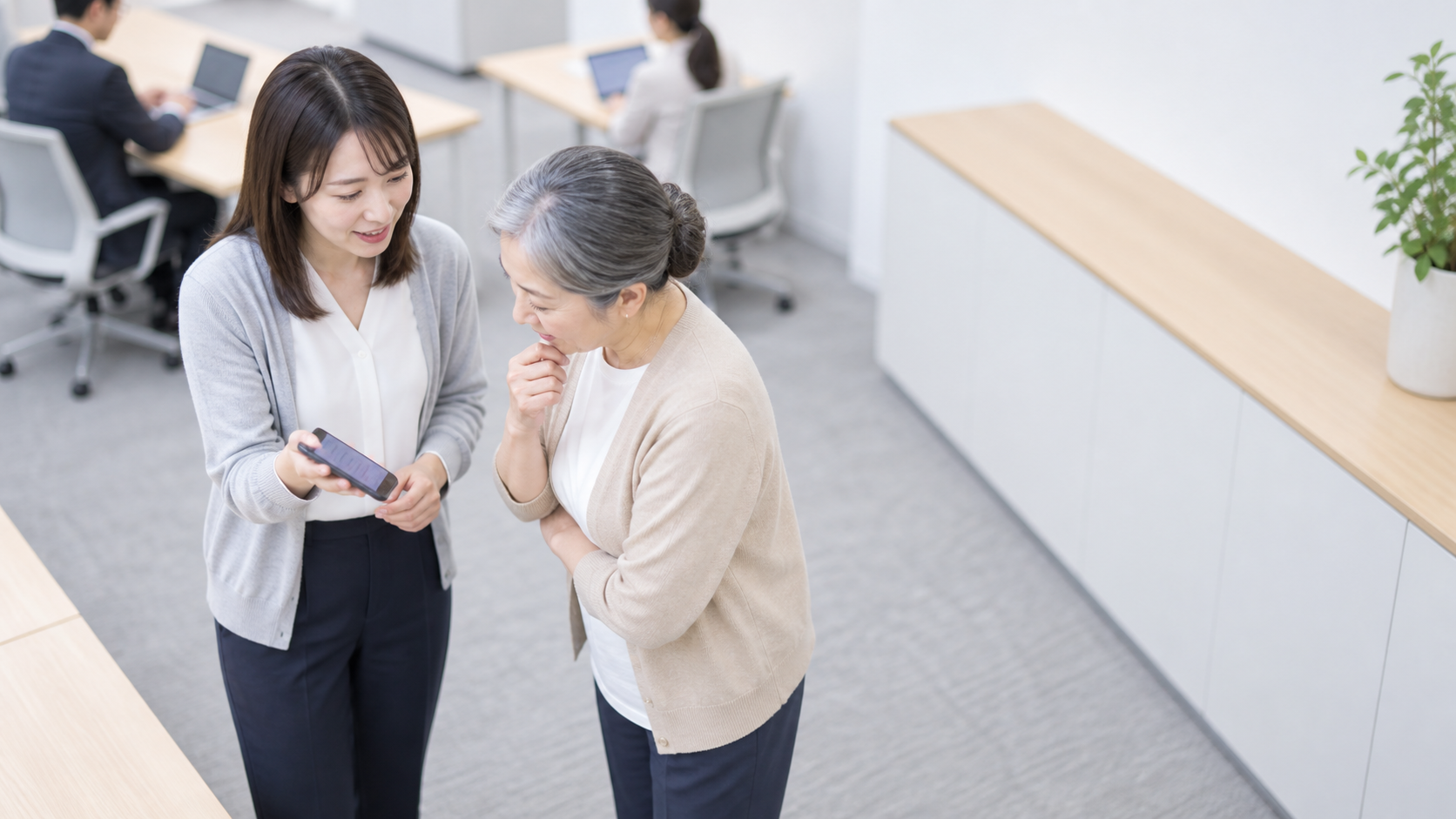 30代前半の日本人女性がスマートフォンの画面提示をしている場面